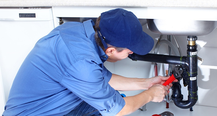 Plumber in Blue Under Sink