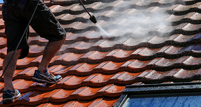 Man in shorts cleaning roof