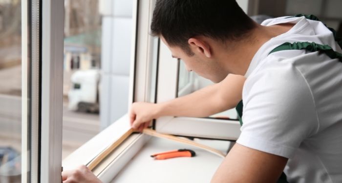 man measuring a window frame