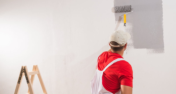 man painting a wall grey