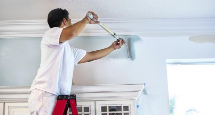 person painting top of wall grey