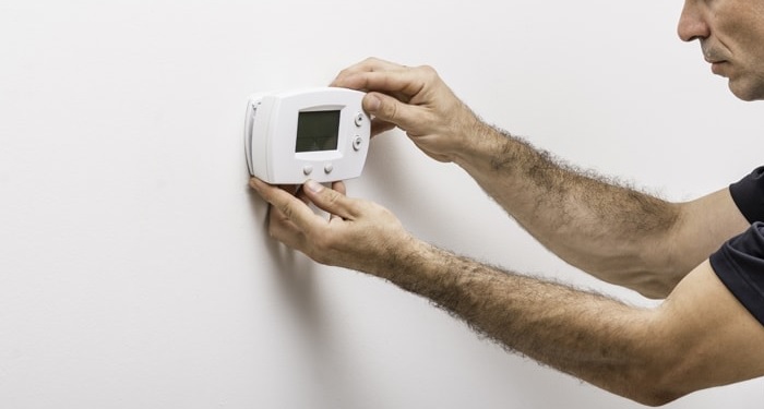 Man installing a thermostat on wall