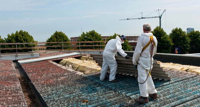 two people removing asbestos off a roof