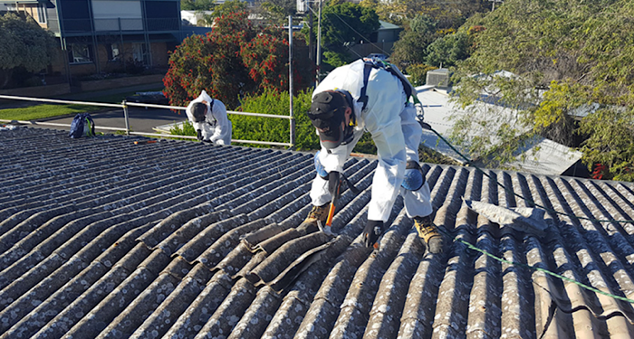 man removing asbestos with a hammer