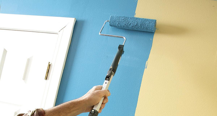 person painting wall blue with long roller