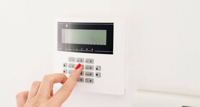 Woman typing in alarm code on home security system