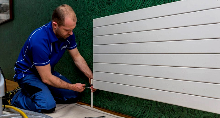 Plumber in Blue Draining Radiator