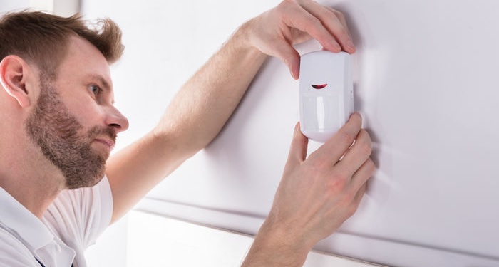 Man removing alarm system on wall