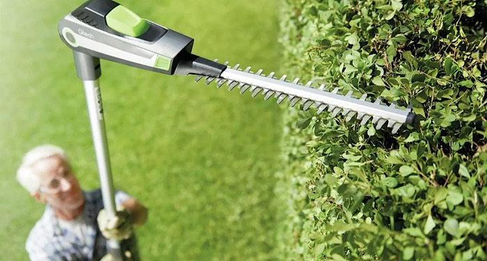 man trimming a high hedge