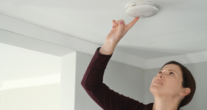Woman testing smoke alarm