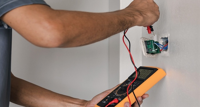 Man testing electrical outlet with multimeter