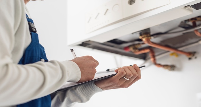 man holding clipboard in front of boiler