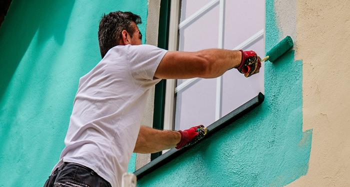 Man painting house green