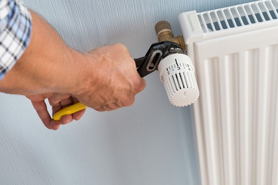 person using wrench on radiator