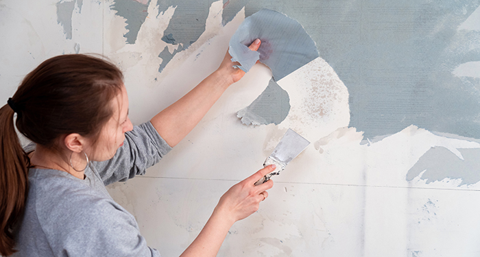 person scraping wet wallpaper