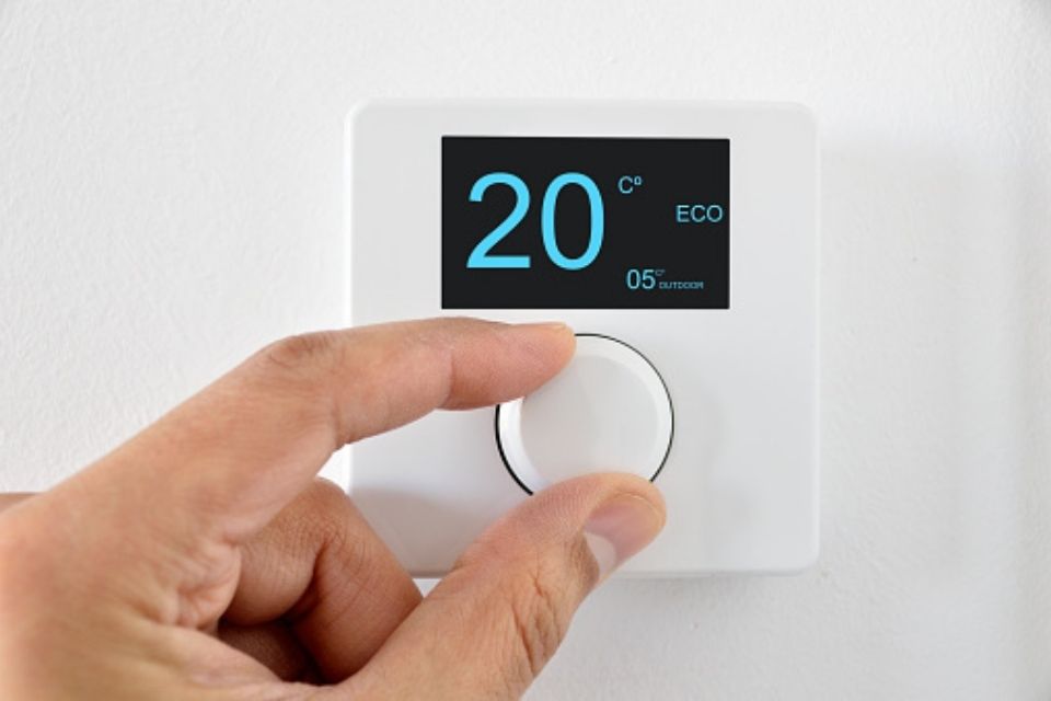 Hand controlling thermostat on wall