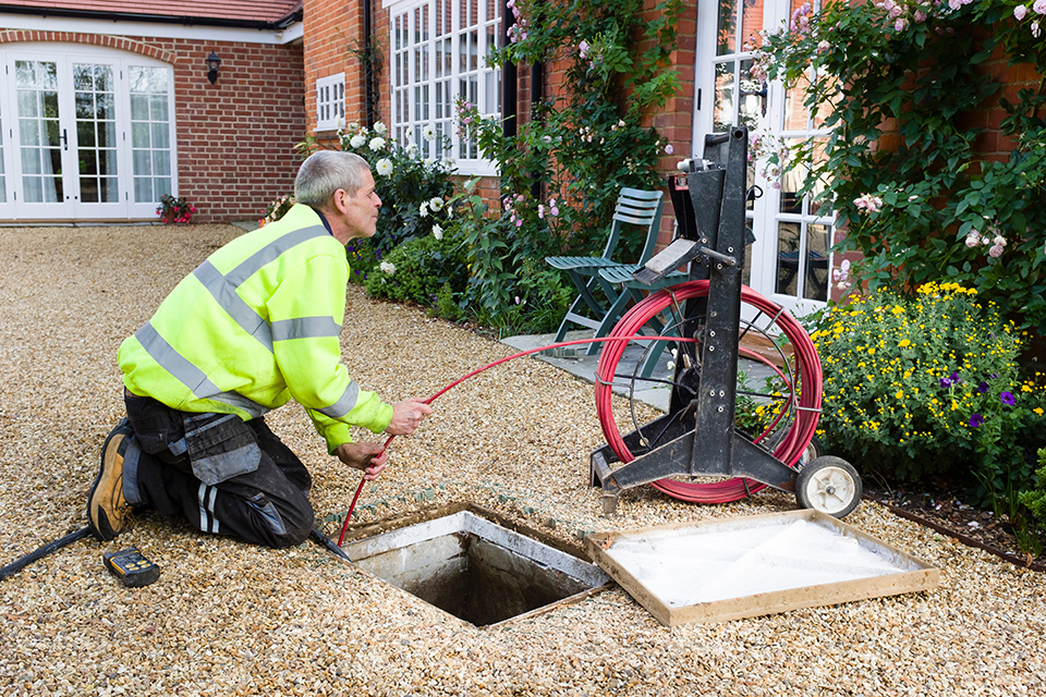 person unblocking drain in hi-vis