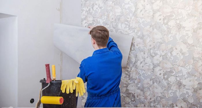 man wallpapering a wall